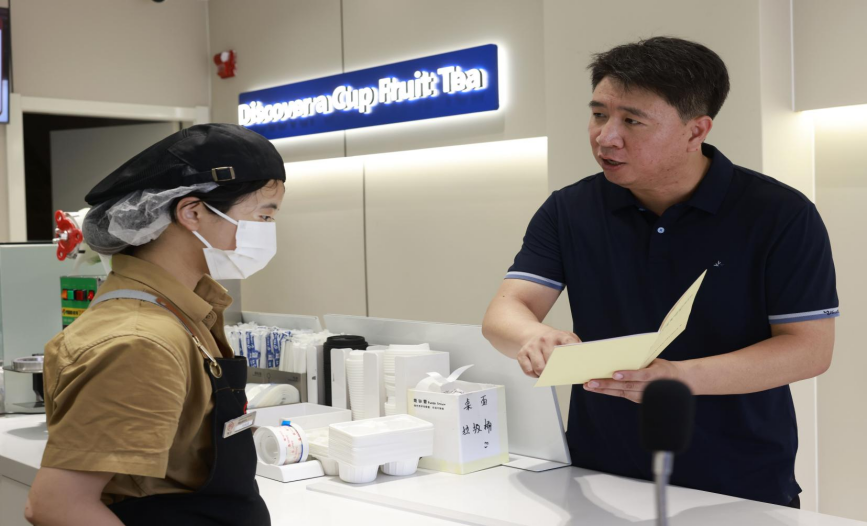 工作人員走進店鋪宣傳“防范非法集資”知識。楊晨攝