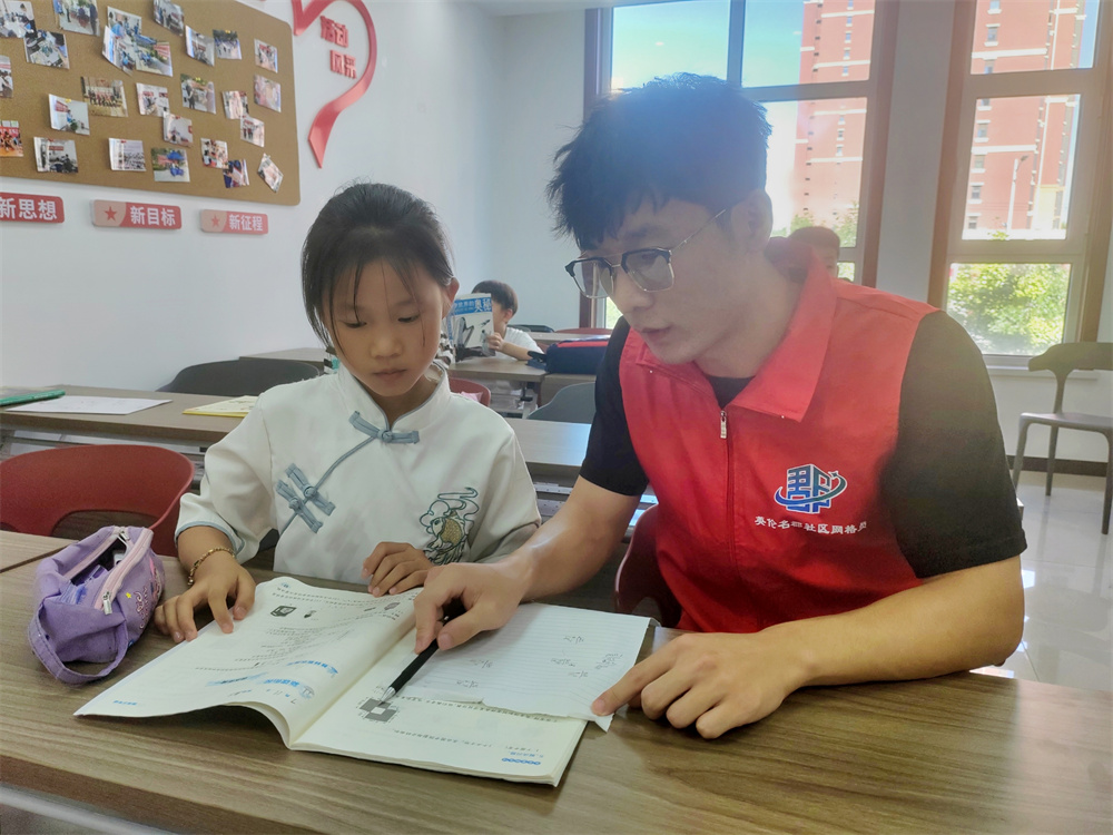 7月17日，在河北省高碑店市东盛街道英伦名郡社区党群服务中心，大学生志愿者正在指导辖区内的孩子做暑期作业。朱珊珊摄