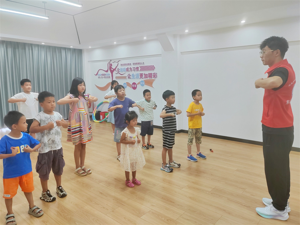 7月17日，在河北省高碑店市东盛街道英伦名郡社区党群服务中心，大学生志愿者正在带领孩子们做运动。朱珊珊摄