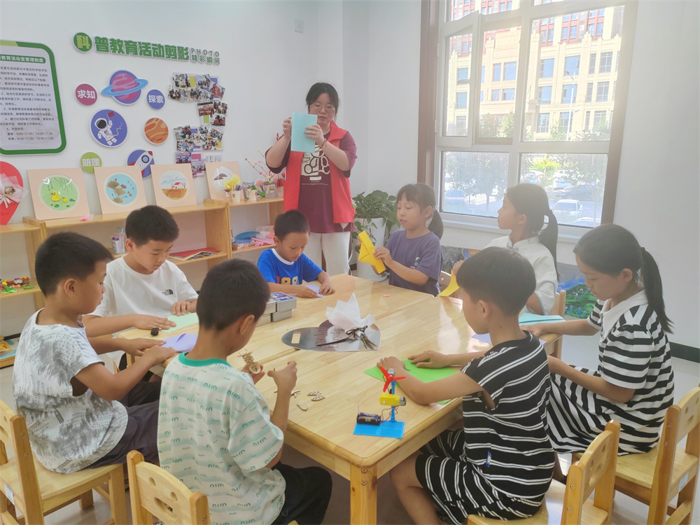 7月17日，在河北省高碑店市东盛街道英伦名郡社区党群服务中心，大学生志愿者正在带领孩子们做手工。朱珊珊摄