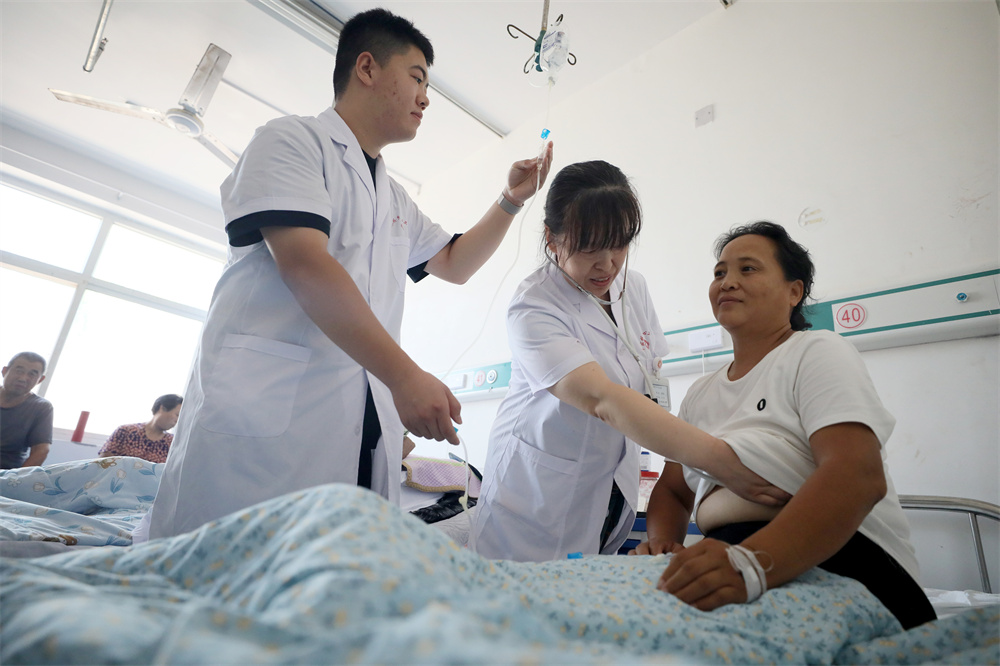 7月21日，在河北省隆尧县牛家桥乡中心卫生院，医生正在给入院治疗的家签病人检查身体。张岭摄
