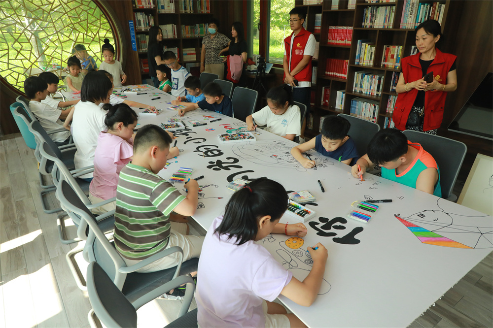 7月27日，在高碑店市植物園的智慧書屋，美術老師與社區志願者共同指導孩子們繪畫。馬凱攝