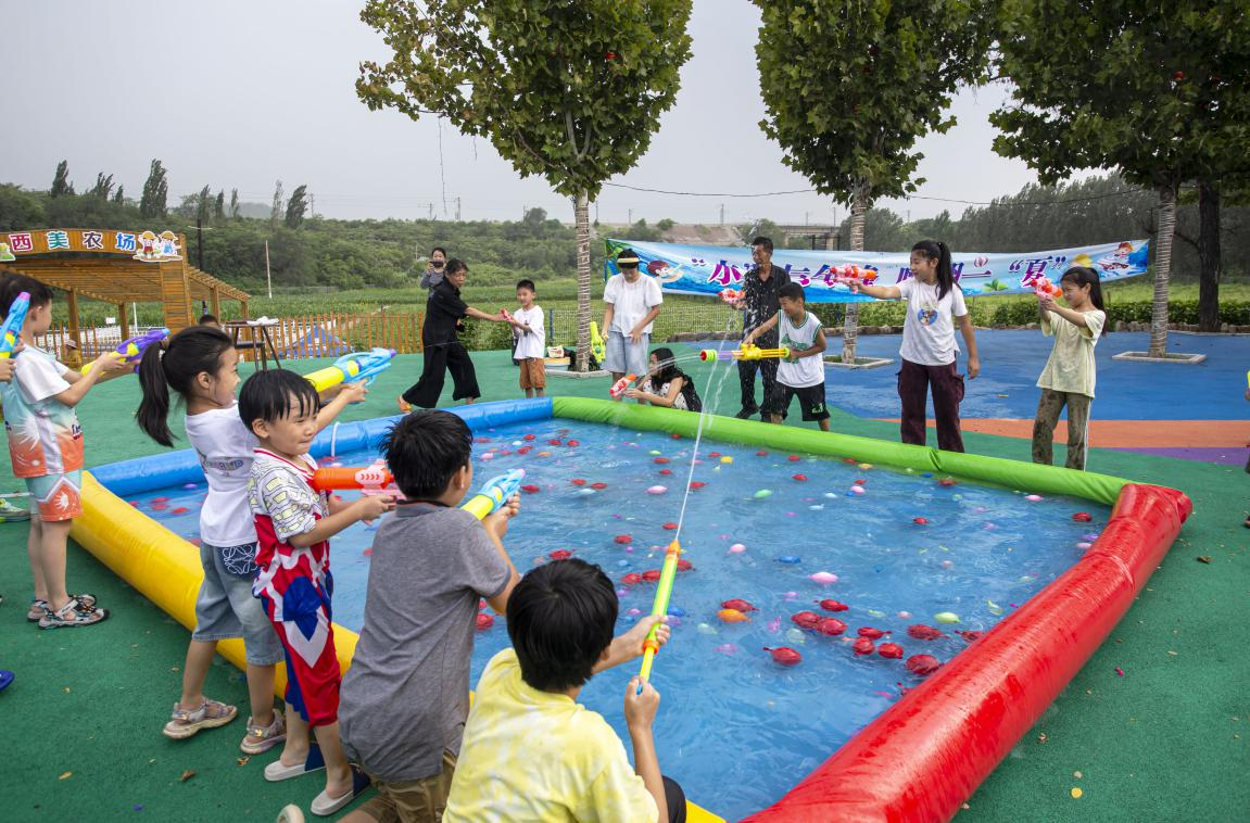 8月6日，河北省邯郸市复兴区二六七二街道大河坡村，放暑假的孩子们在简易储水池玩水枪大战。聂长青摄