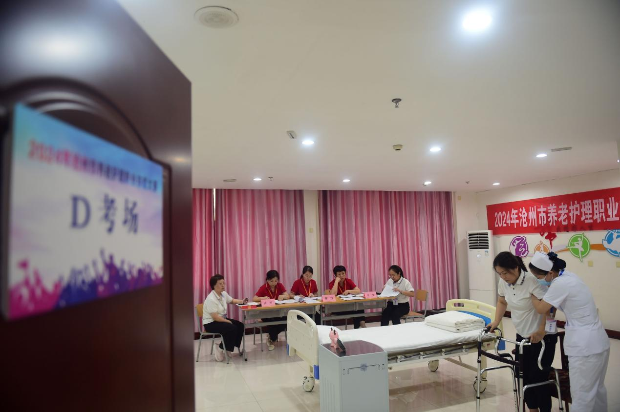 参赛选手在演示帮助老人使用行走助力器。傅新春摄