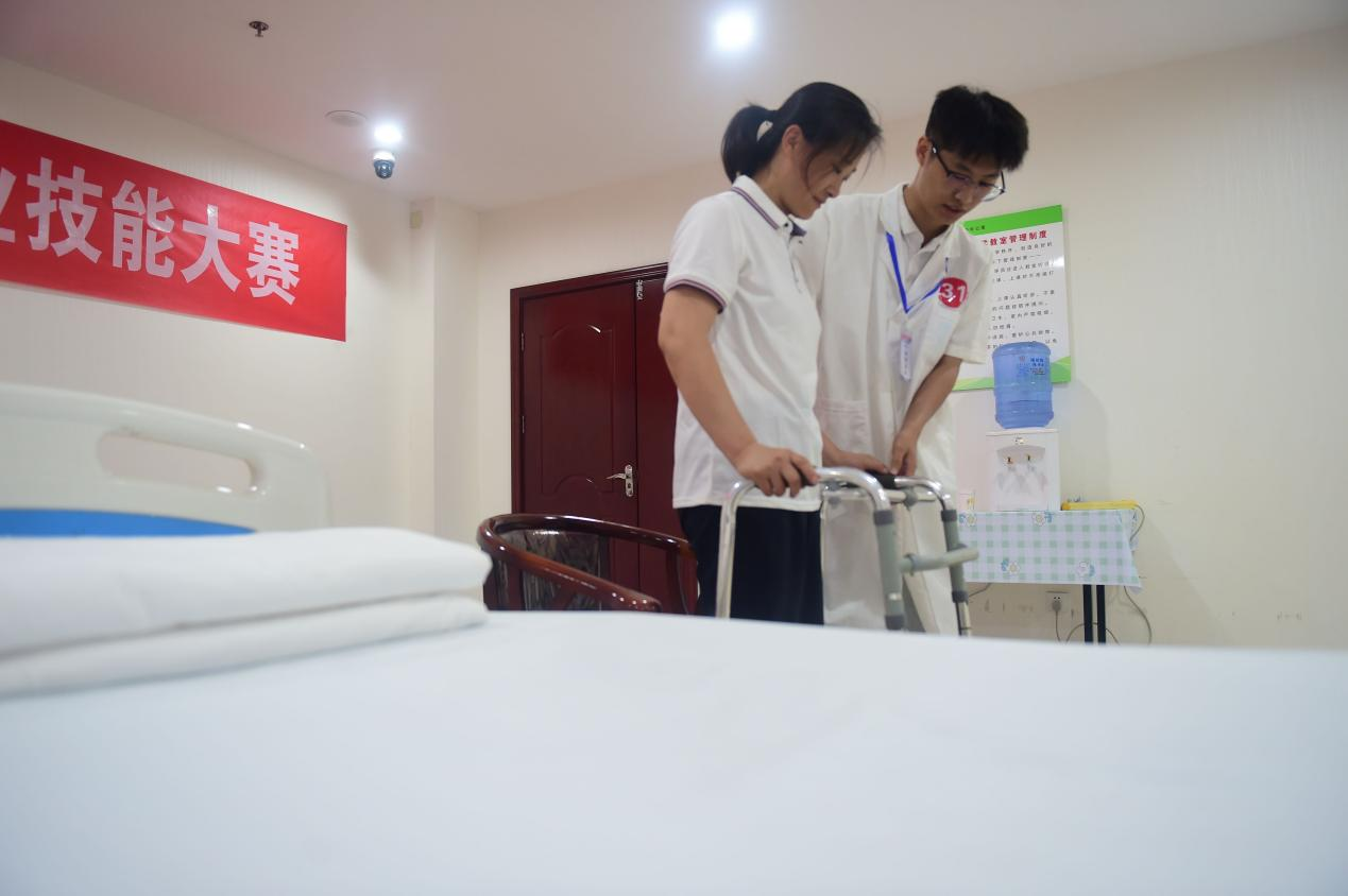 参赛选手在演示帮助老人使用行走助力器。傅新春摄
