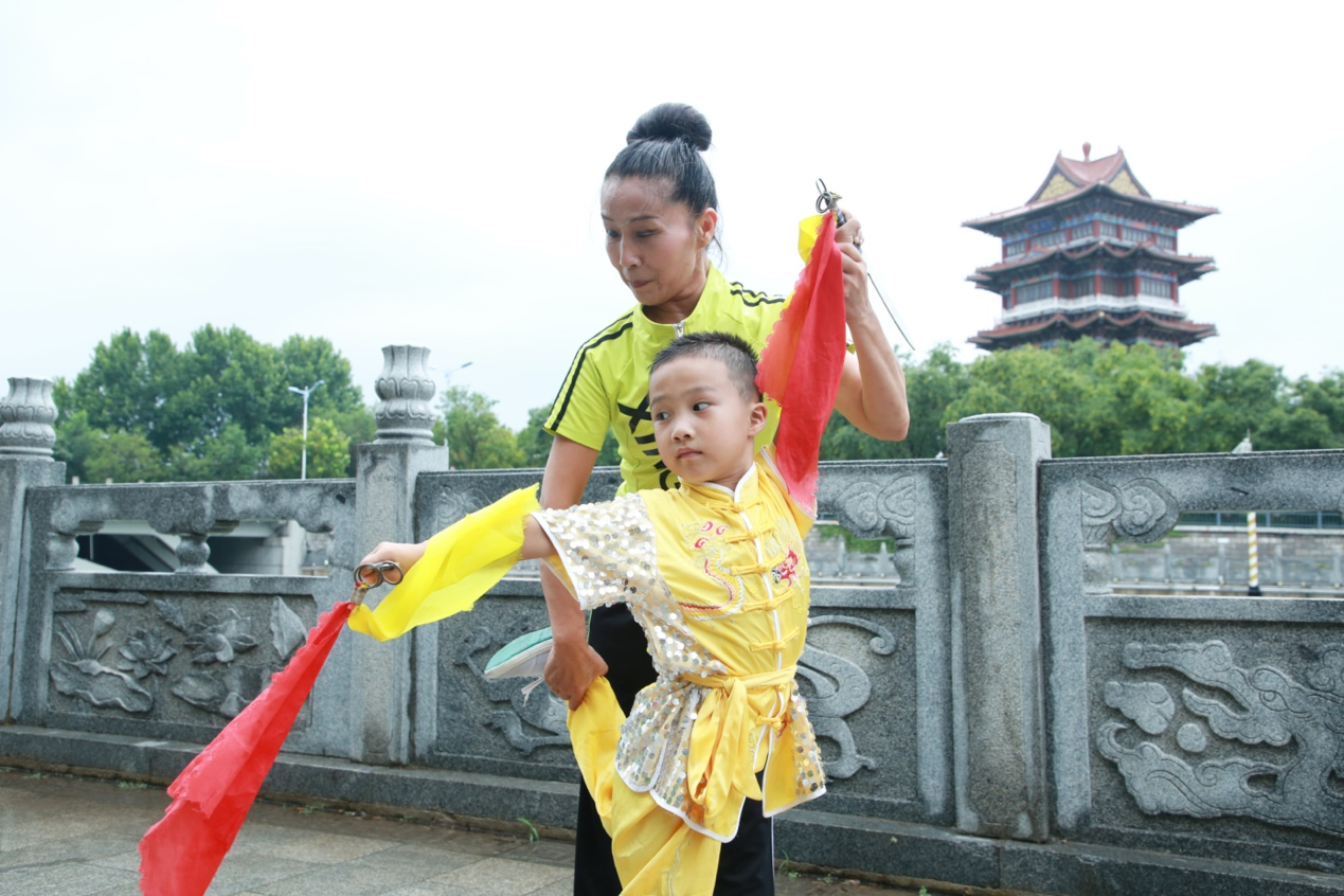 8月19日,六岁参赛小选手支晟睿正在拦手长穗双剑传承人汪娟的指导下训练。殷实摄