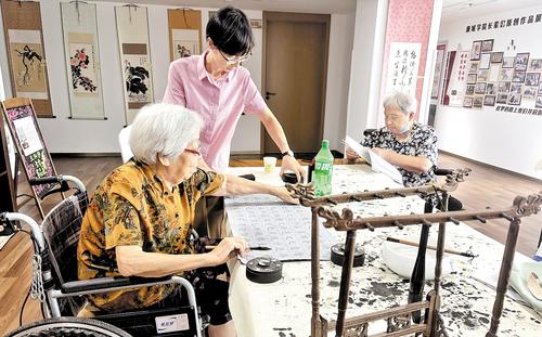 8月17日，89歲的王淑珍老人（左一）正在保定陽光康城頤養中心的書畫室裡練習書法，牆上展示的就是她的作品。 本報記者 李 巍攝