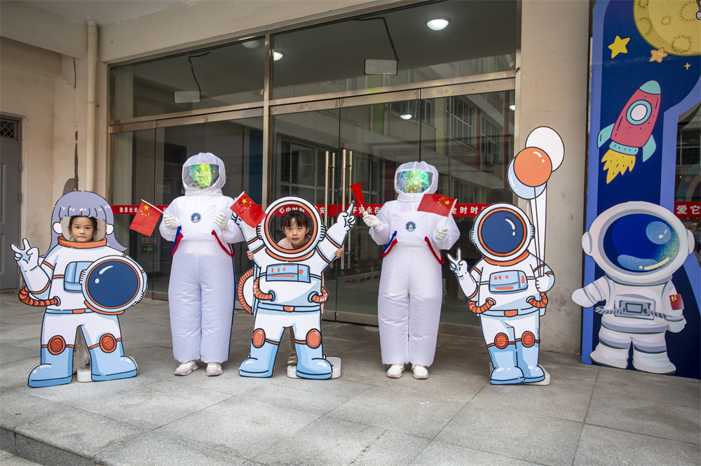 8月31日，河北省邯郸市复兴区百花第二小学，身穿太空服的学生与一年级学生在卡通太空人前留念。聂长青摄