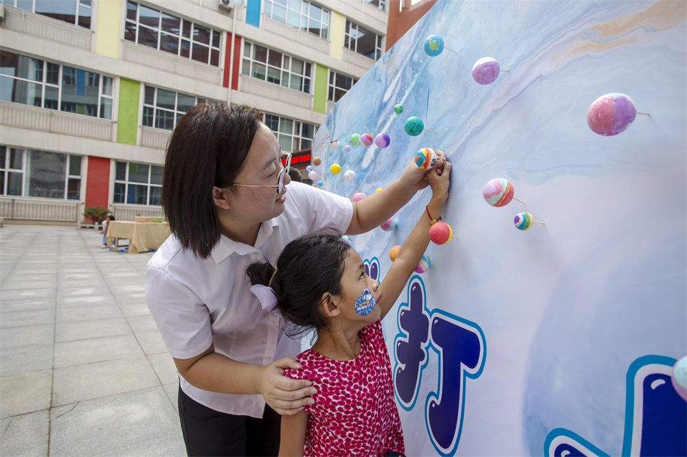 8月31日,河北省邯郸市复兴区百花第二小学,一年级学生在太空展板前描绘自己心目中的星球。聂长青摄