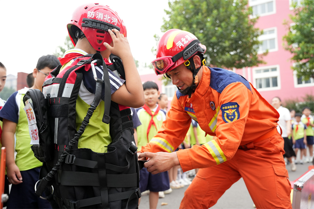 9月1日，河北省隆堯縣第二實驗小學消防安全第一課活動現場，消防員在演示穿戴消防衣。王鑠攝