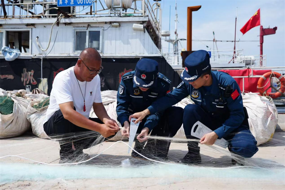 唐山海警局执法员进行渔网的网目尺寸测量。李福政摄