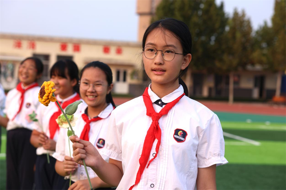 学生们手持手工花同唱《我和我的祖国》。杨晨摄