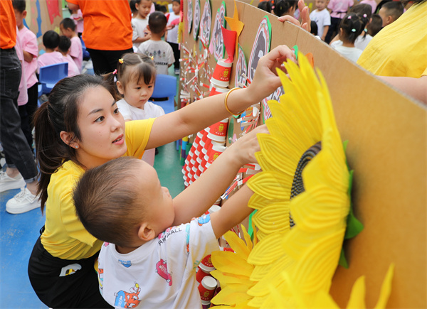 9月25日,幼儿园老师在指导孩子们装饰文化墙。田博摄