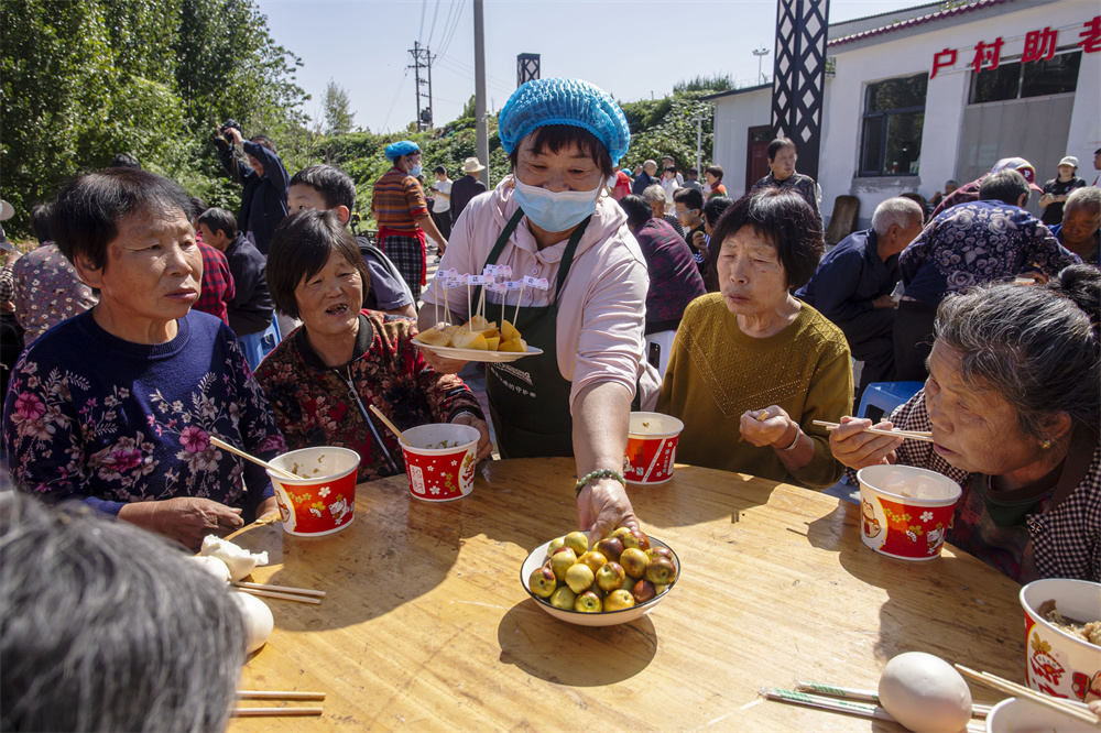 10月1日，河北省邯郸市复兴区户村镇户村村，厨师为老年人端水果。聂长青摄