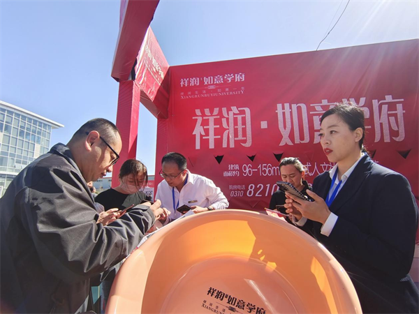 在一家房地产促销展位前，工作人员正在向群众介绍购房优惠政策。霍飞飞摄