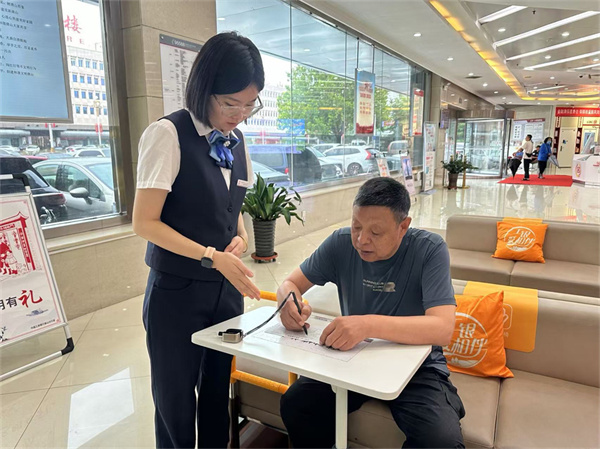 工行唐山凤凰支行客户经理指导老年客户在移动填单台填写业务凭证。李熙美摄