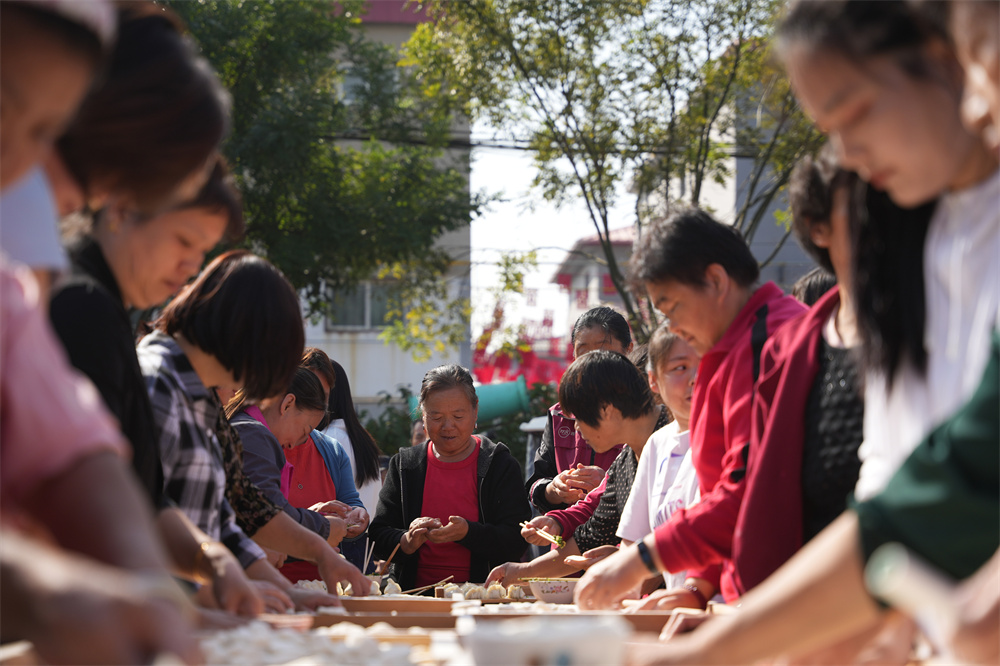 10月11日,在隆堯縣隆堯鎮東河村第十三屆百人餃子宴,志願者正在為老人包餃子。王鑠攝
