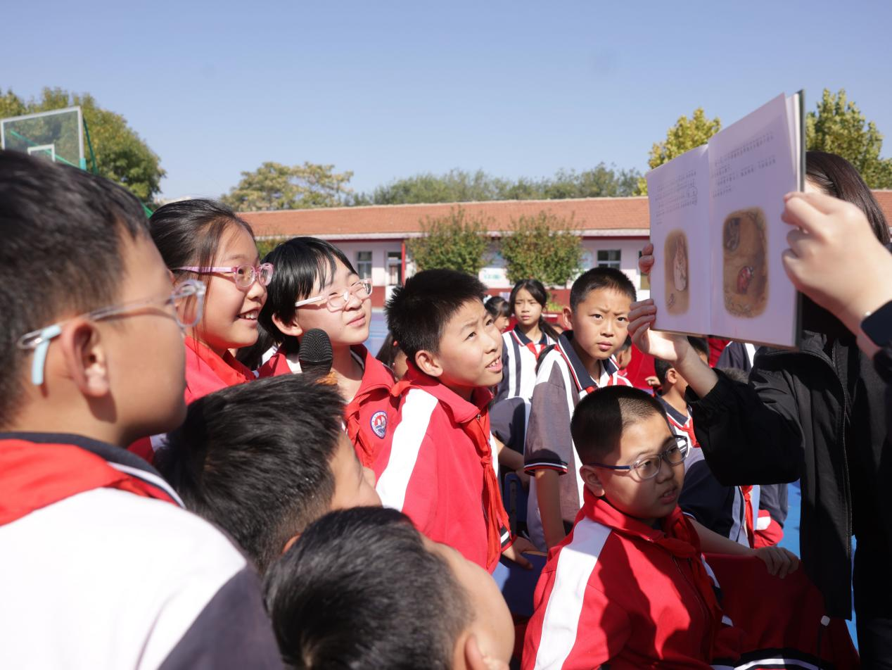 工作人员与学生们近距离互动，展示盗版书籍存在的错误，提醒学生购买正版书籍。杨晨摄