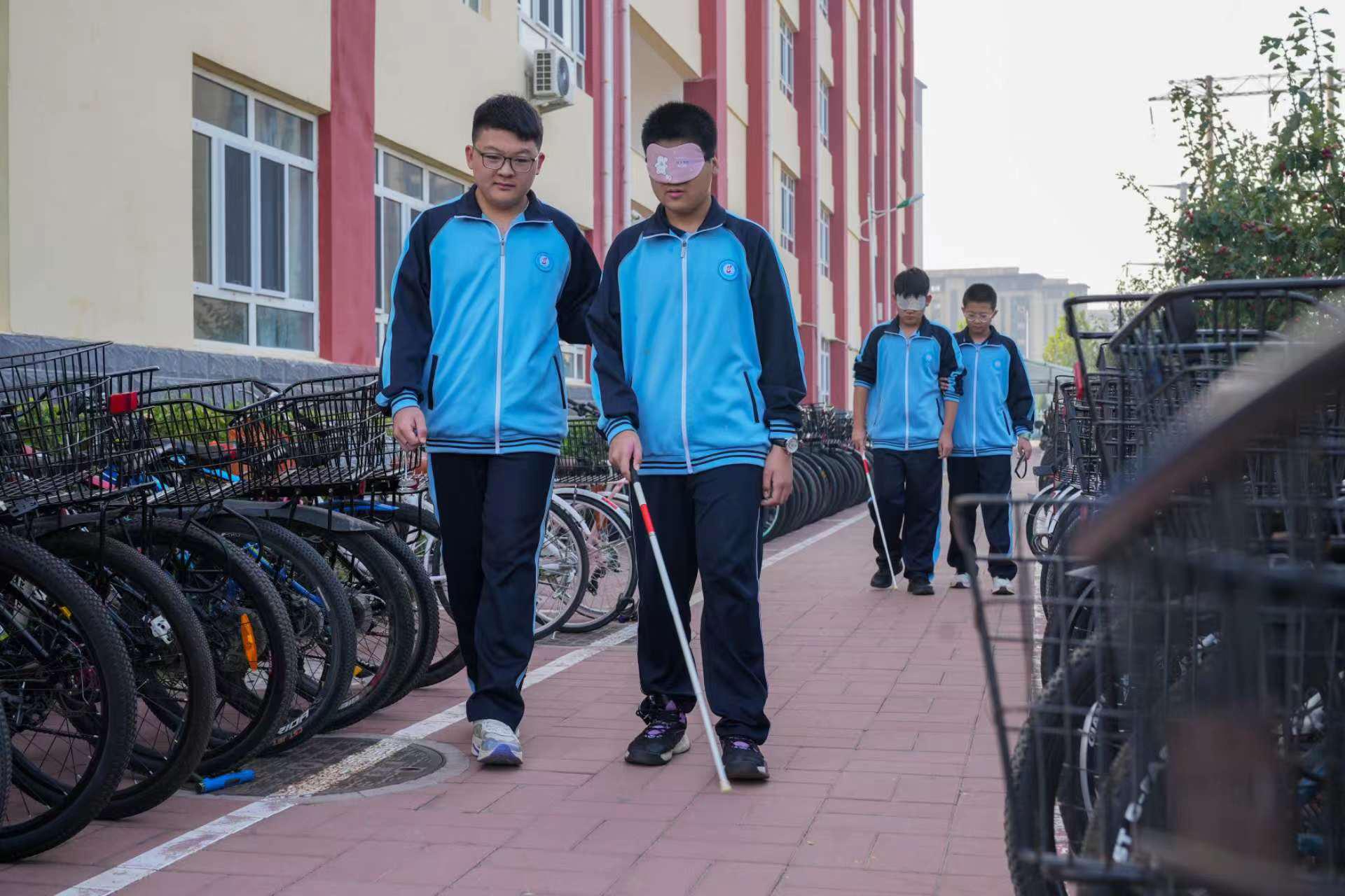 任丘市第八中学学生在校园里戴着眼罩体验盲人行走。韩慧峰摄