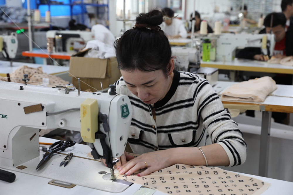 工人在京津轉移服裝企業縫紉車間工作。田博攝