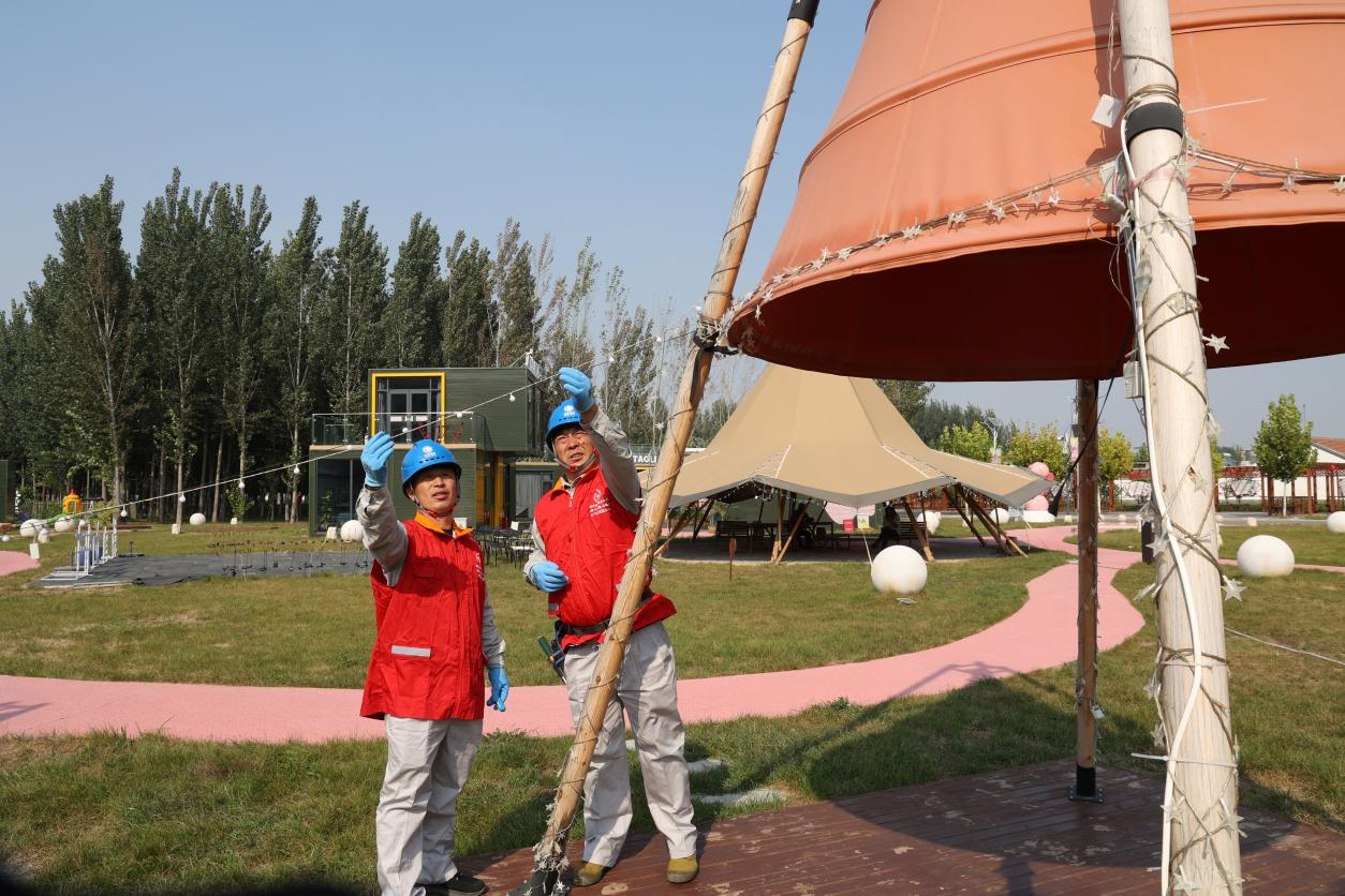 电力工人在丰南区南孙庄镇桃里乡村音乐节现场检查照明线路。周宇翔摄