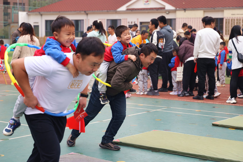 孩子與家長相互配合，“負重前行”，奮勇爭先。楊洋攝