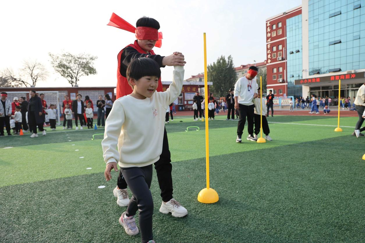 小学生在进行“牵引盲跑”项目的比赛。辛军摄
