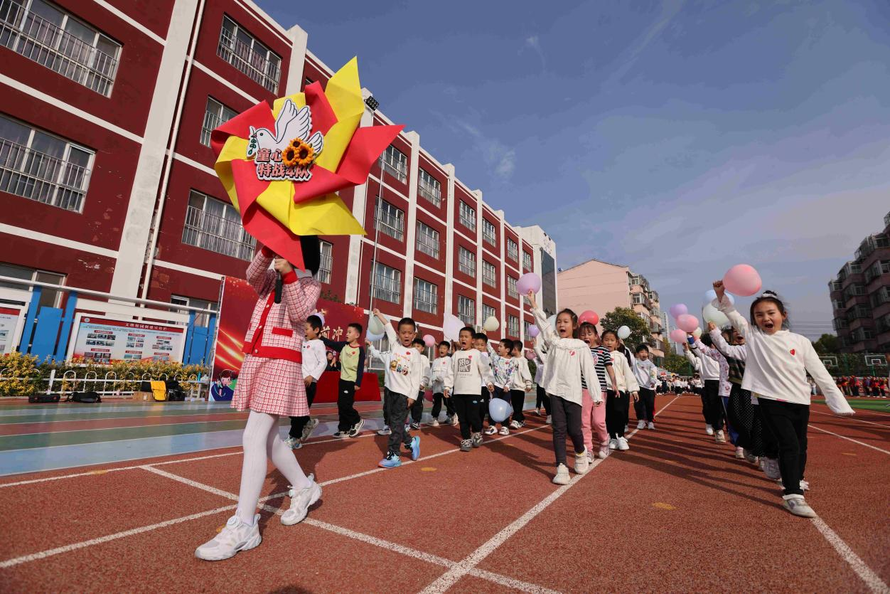 参加趣味运动会的小学生们高兴地进入比赛场地。辛军摄