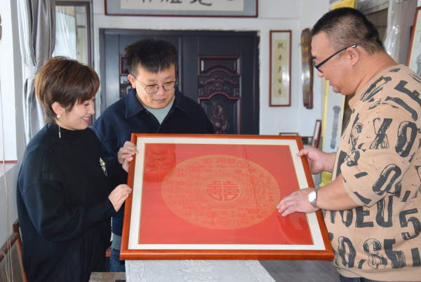 刘东东（中）、袁木兰（左）在结婚十年纪念日向杨威（右）定制金石传拓“百喜图”。董攀摄