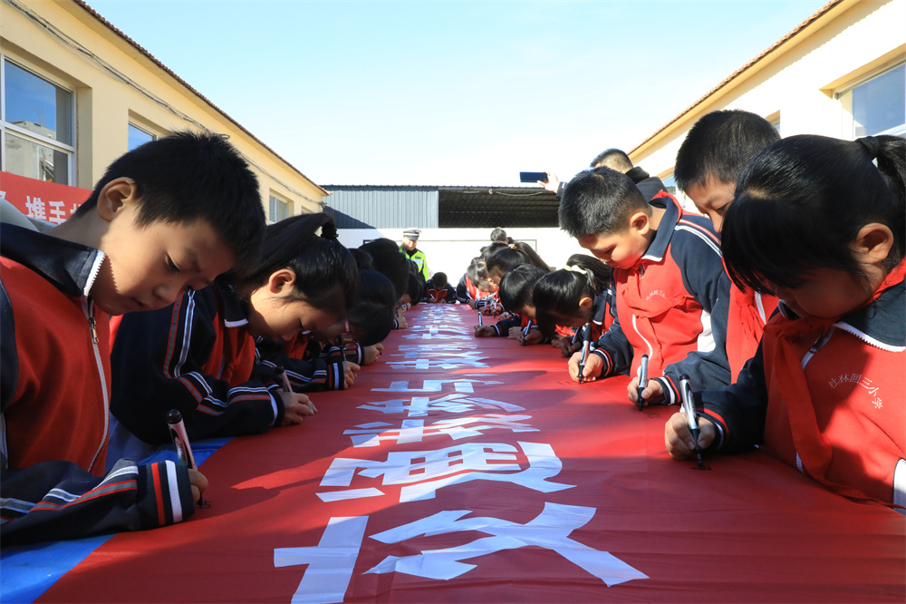 11月26日，小學生在交通安全倡議條幅上簽名。劉金忠攝