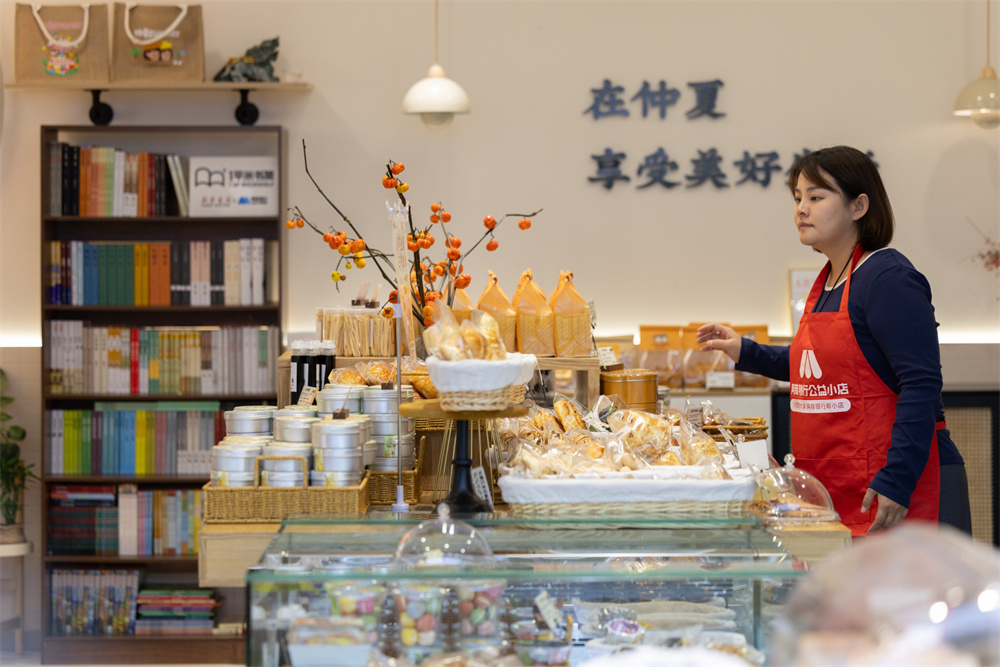 仲夏一心蛋糕面包集合店店主康盼盼騰出店裡最好的位置放置書架。主辦方供圖