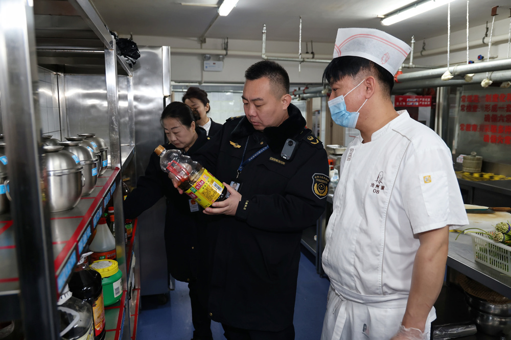 执法人员正在对年夜饭承接餐饮单位的环境卫生、食品留样等进行监督检查。杨洋摄