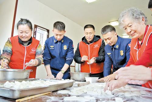 1月24日，在滄州市消防救援支隊浮陽北大道特勤站，“中國好人”崔建鬆（左三）帶領滄州市義務工作者協會志願者和特勤站消防指戰員一起包餃子。 本報記者 王雅楠攝