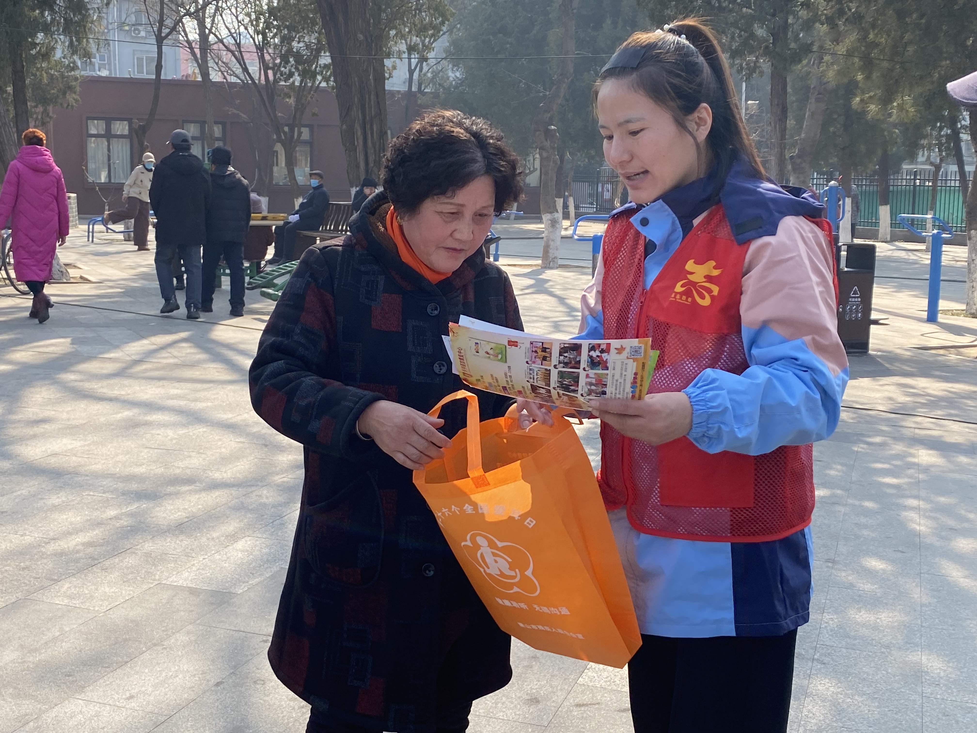 在建华二社区活动现场，志愿者正在向社区群众解读惠残政策。张宗鸣摄