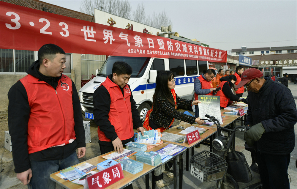 志愿者设立宣传站台，向逛集市的村民发放宣传手册。梁玉水摄