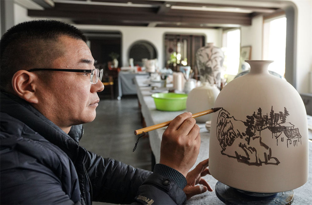 画家在陶瓷胎体上创作。陈儒摄