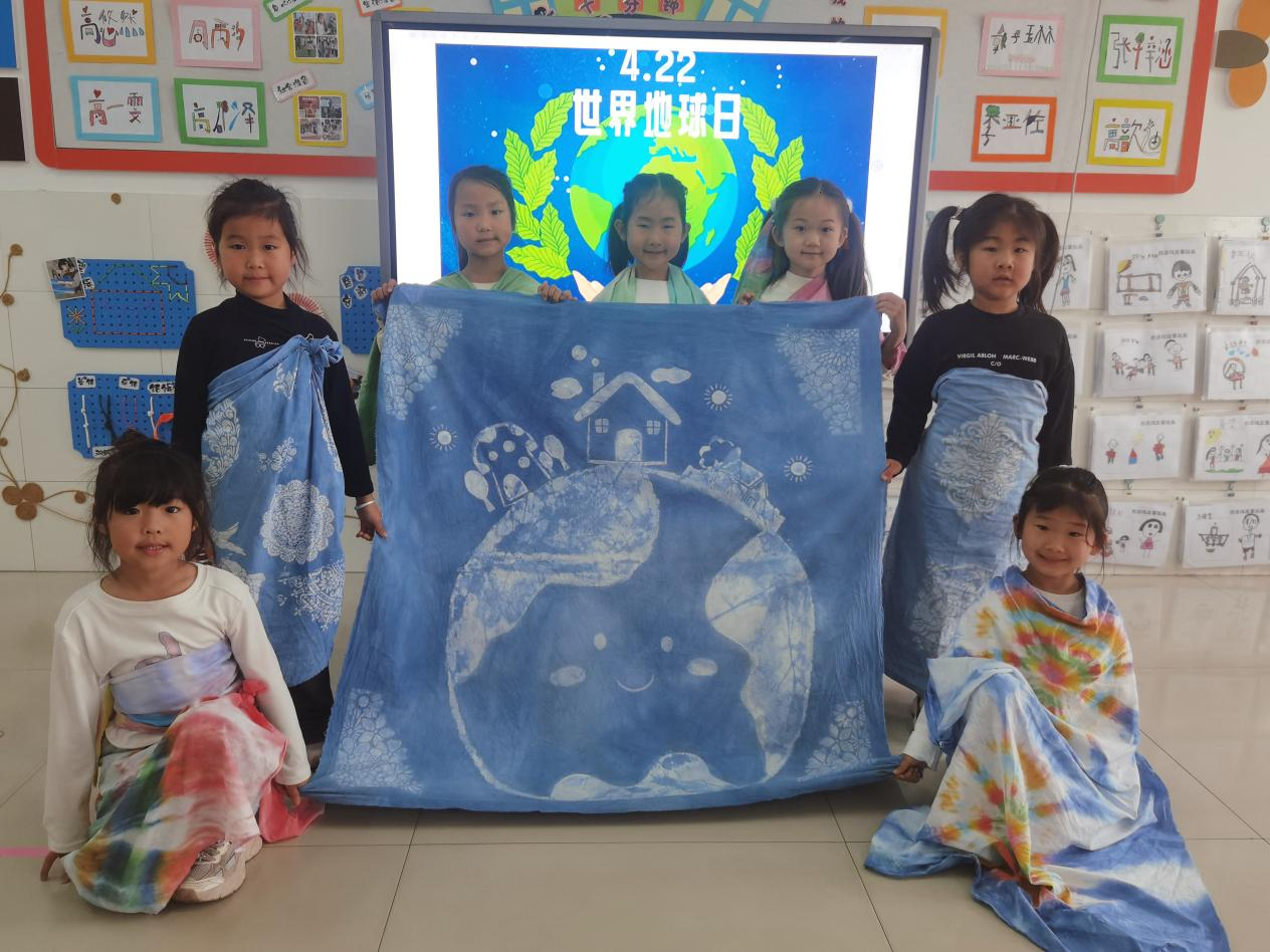 黑沿子中心幼儿园的孩子们展示扎染创作的地球日主题服装。祁云摄