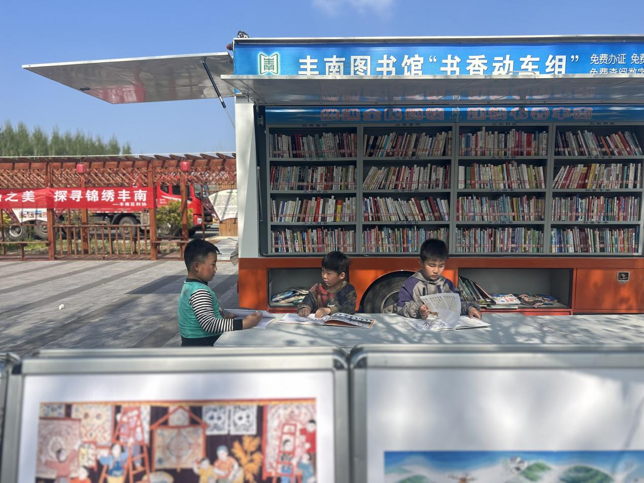 丰南区南孙庄镇赵新庄村的孩子们在流动图书车前读书。郭远芳摄