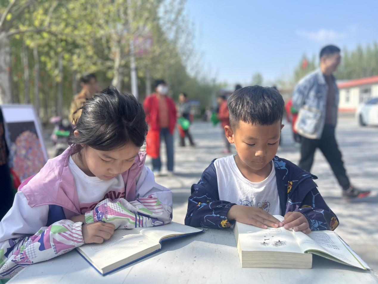 丰南区南孙庄镇赵新庄村的孩子们在流动图书车前看书。郭远芳摄