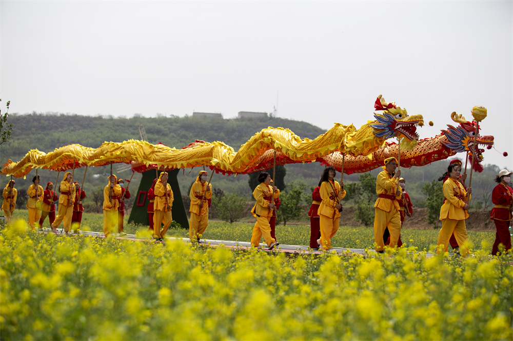 4月26日，河北省邯郸市复兴区二六七二街道东高河村油菜花海，演员为游客表演舞龙节目。聂长青摄