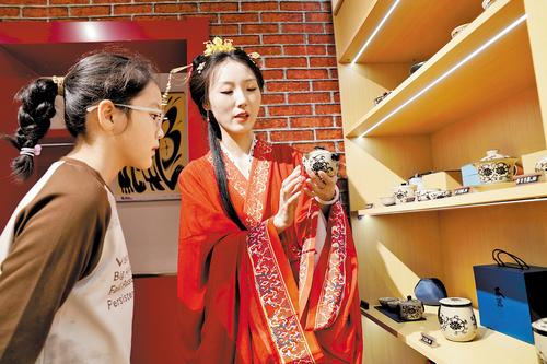 5月1日，邯鄲成語之都·文創旗艦店內，身穿戰國袍的工作人員（右）為顧客介紹磁州窯茶具。本報記者 陳正攝