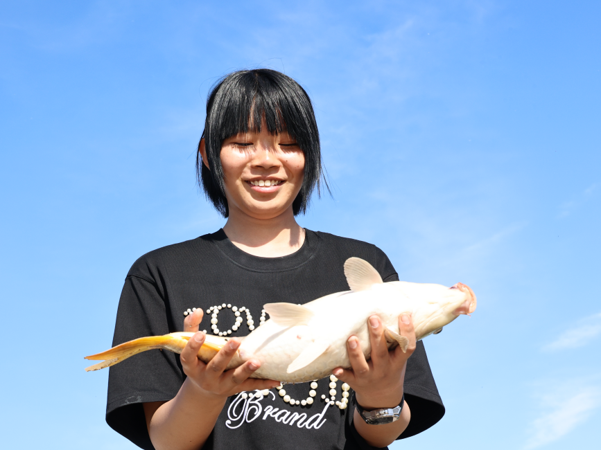 钓鱼爱好者女儿手捧父亲钓的大鱼。滕桂芹摄