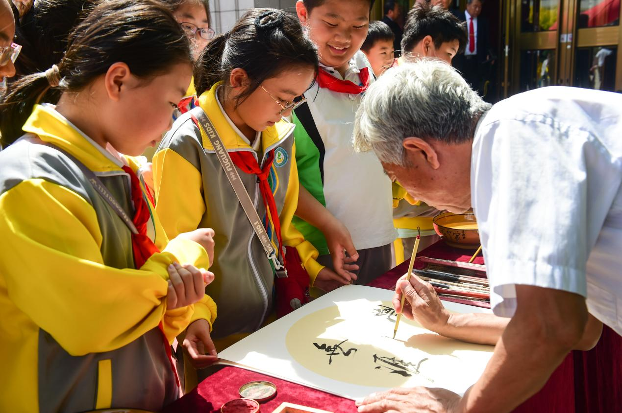 小学生在书法寄语家教家风现场,领取长者“寄语”。傅新春摄