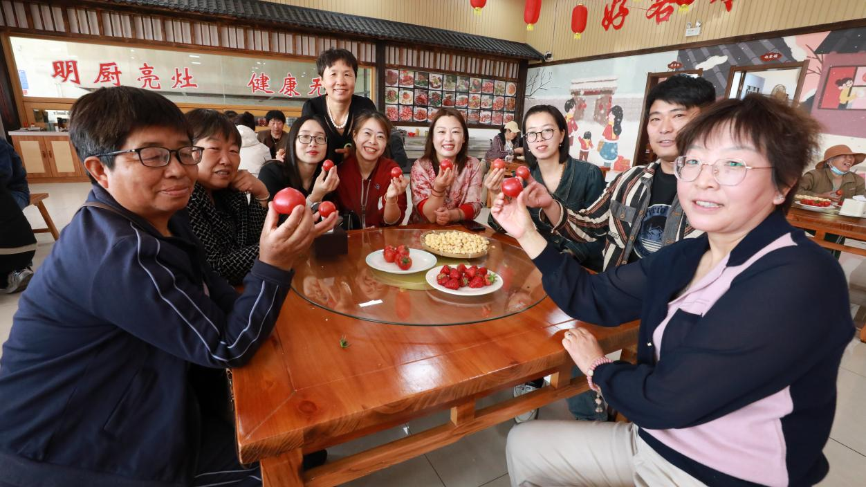 丰南区胥各庄镇岭子上村积分兑换活动现场，村民分享村特色草莓、西红柿。张良摄
