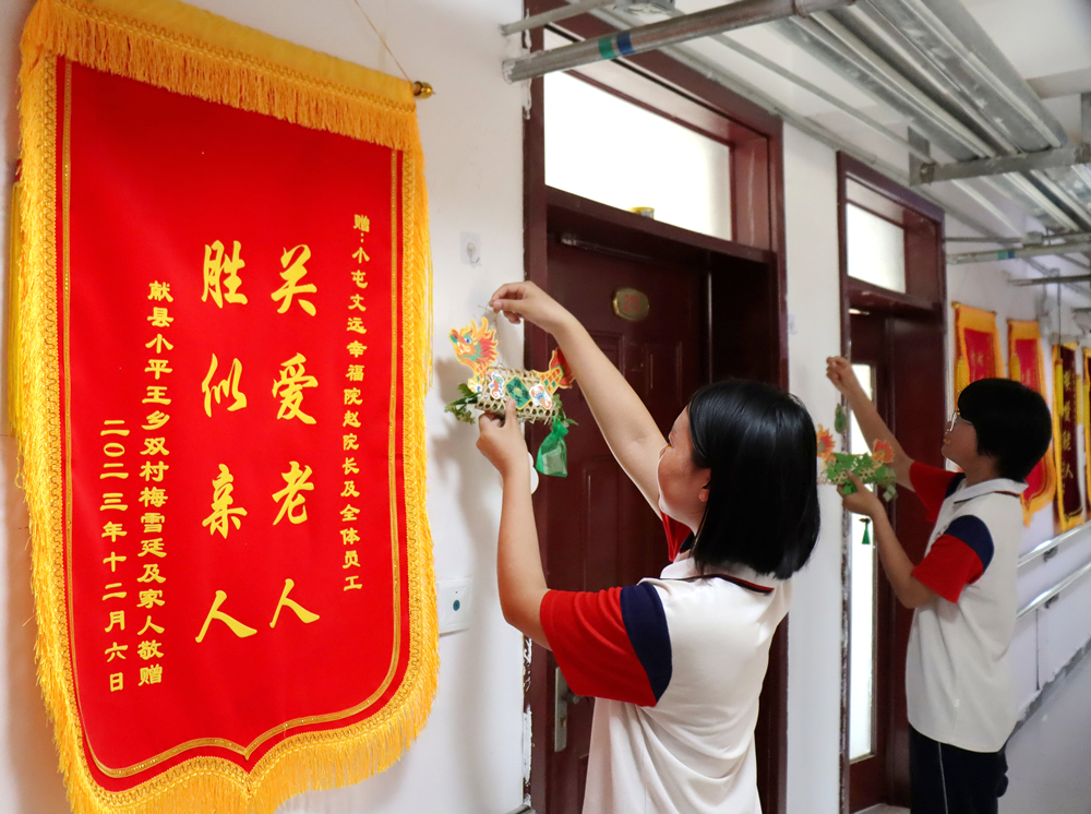 学生在给老人的房间悬挂香囊。李谦摄