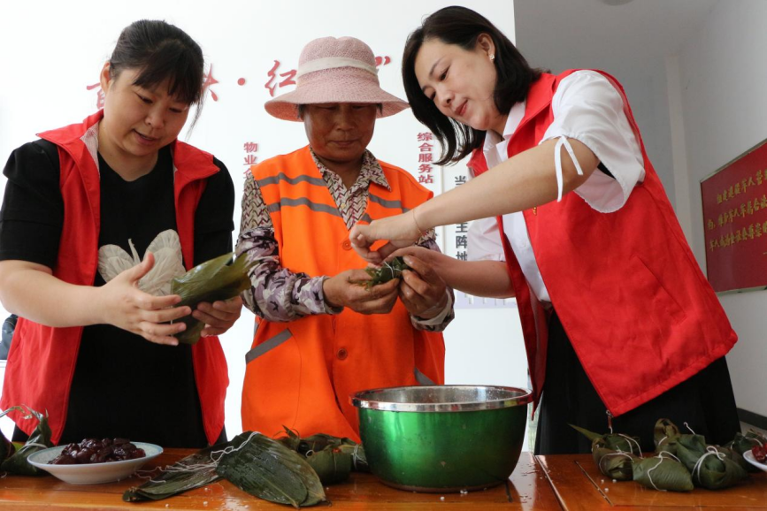 党员志愿者和环卫工人等一起包粽子。张宁摄