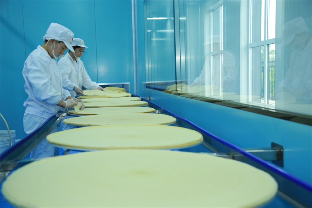 一张张煎饼通过传送带送至醒发车间。殷实摄