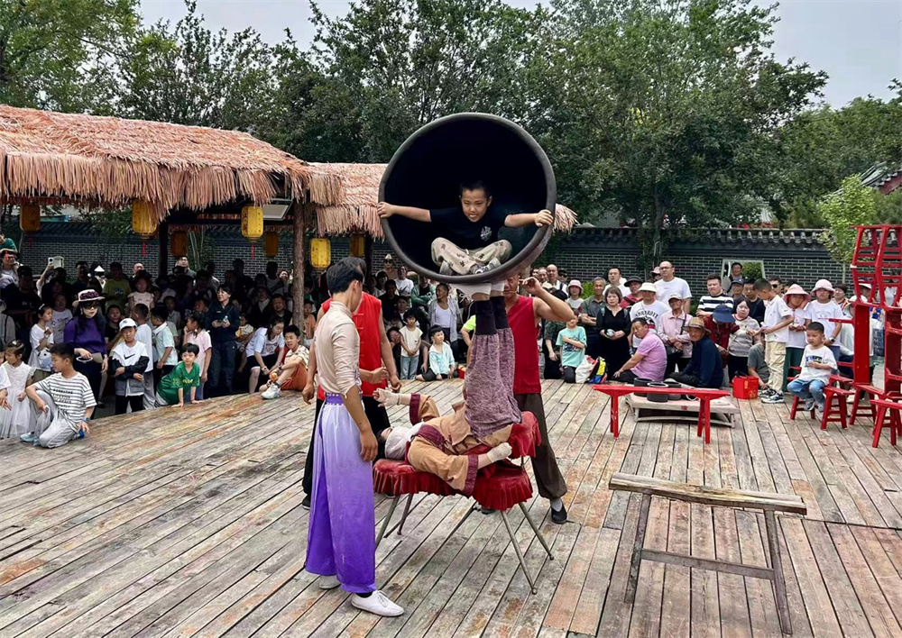 6月1日，在吴桥杂技大世界，一位游客正在与杂技演员进行互动演出。殷实摄