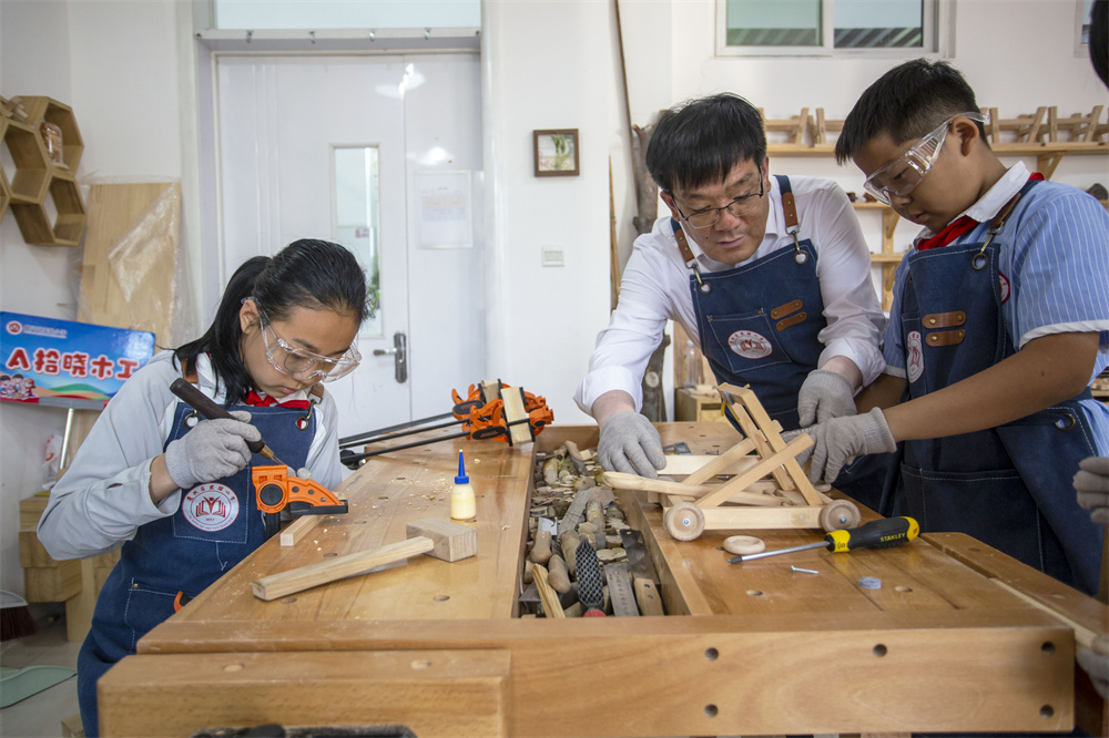 6月12日，河北省邯郸市复兴区实验小学木工教室里，老师（中间）在指导学生“‌榫头卯眼”精准拼接‌。聂长青摄