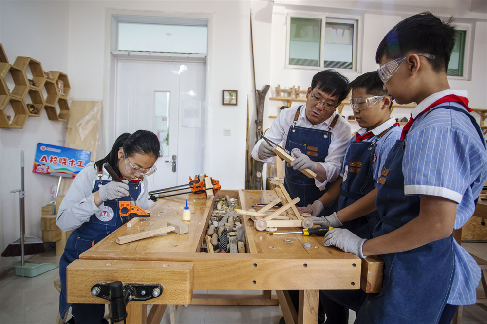 6月12日，河北省邯郸市复兴区实验小学木工教室里，老师（中间）在指导学生“‌榫头卯眼”精准拼接‌。聂长青摄